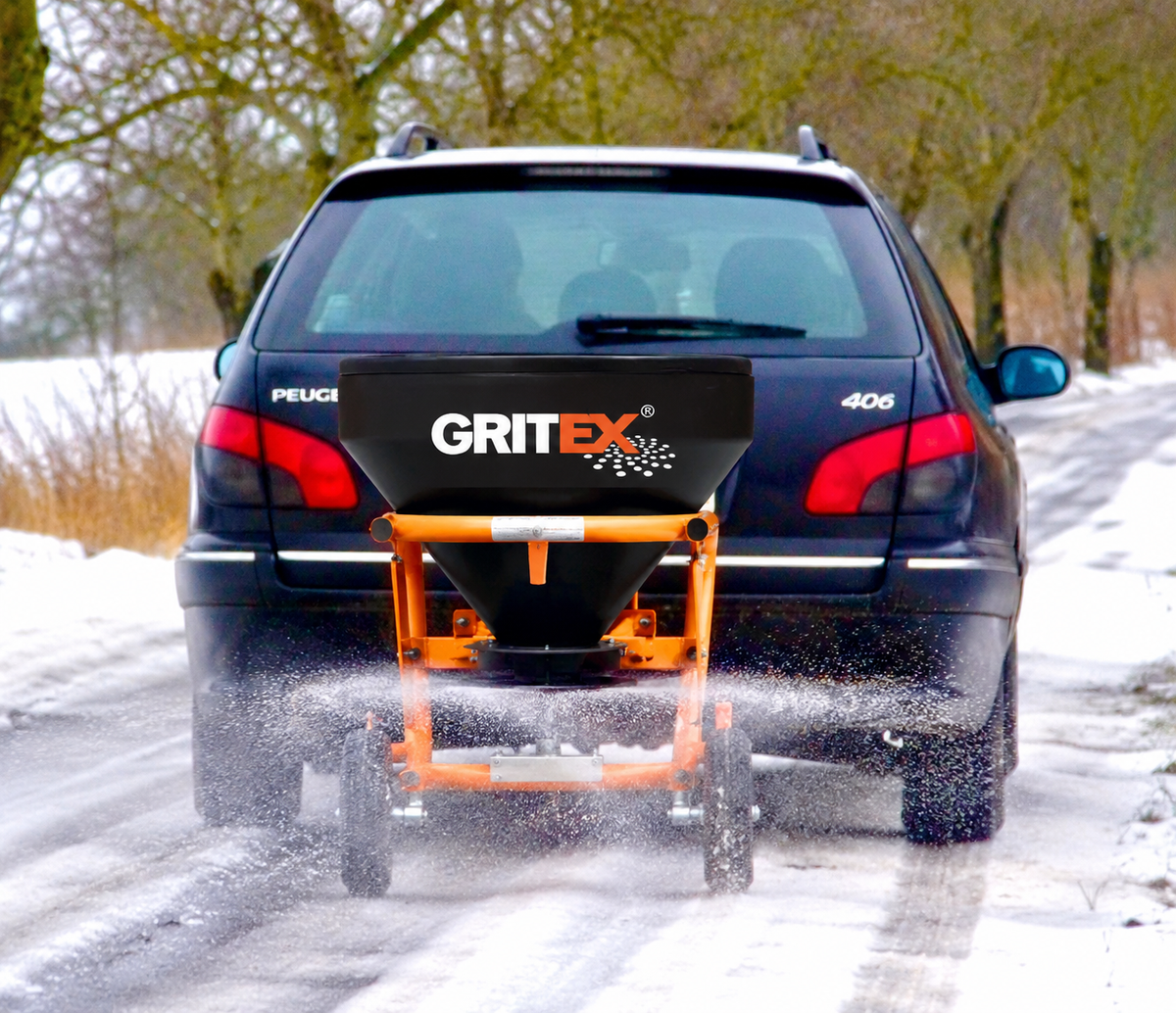 GRITEX salt spreader mounted behind a Peugeot spreading salt on a snowy road