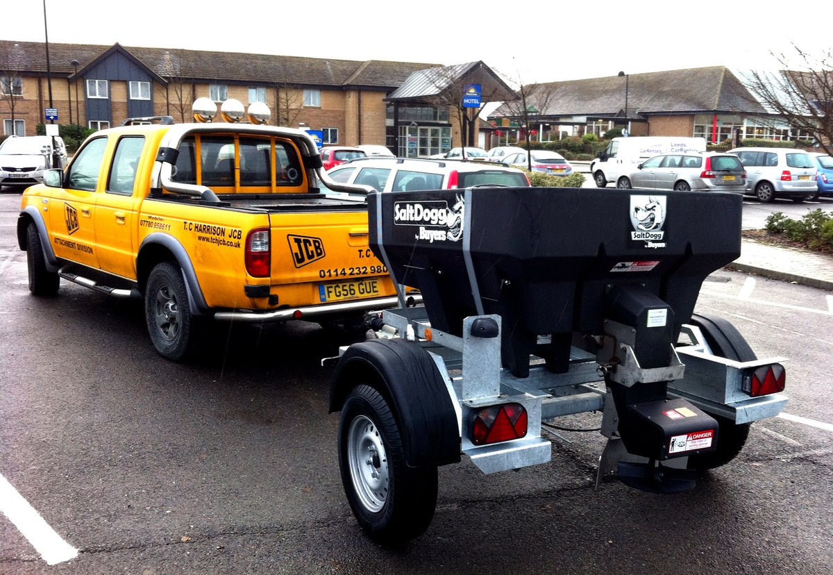 SaltDogg SHPE0750 450L hopper salt spreader mounted on a trailer behind a pickup
