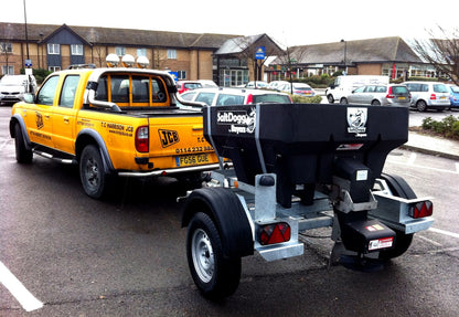 SaltDogg SHPE0750 450L hopper salt spreader mounted on a trailer behind a pickup